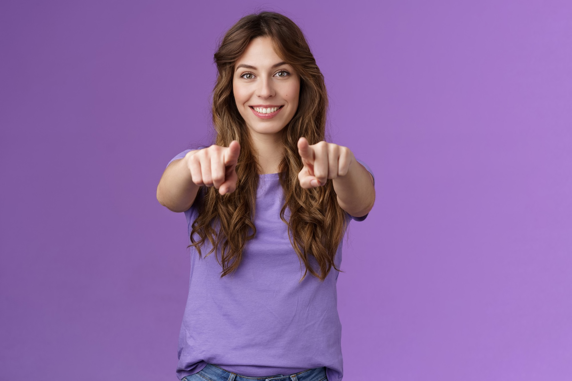 Ragazza con capelli lunghi punta gli indici verso chi guarda